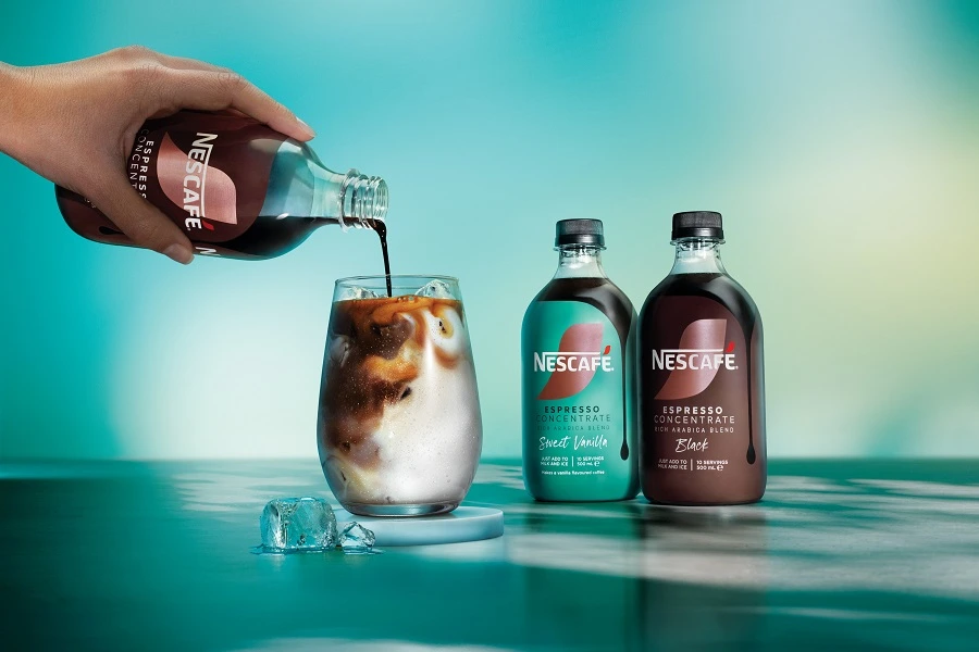 pouring nespresso concentrate into a glass of milk